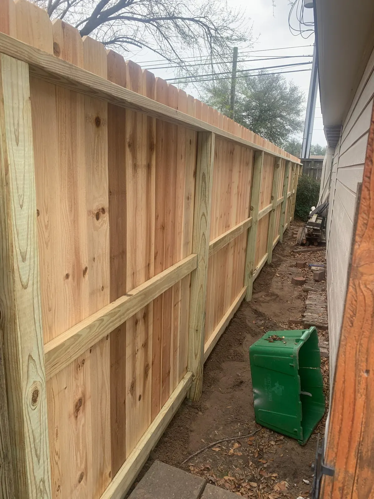 New cedar picket fence with a top cap alongside a house in north Katy