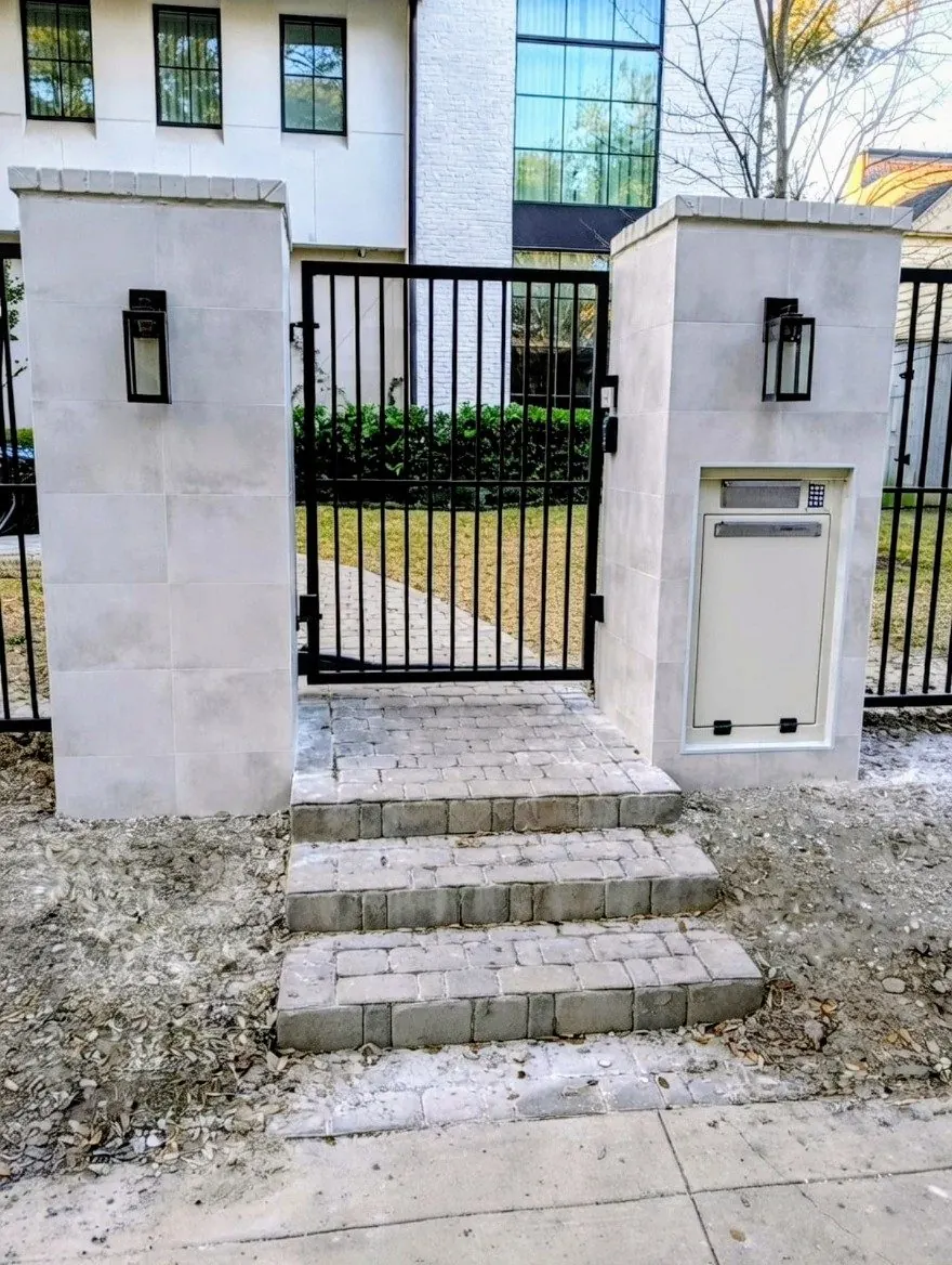 Stone entry columns with lanterns, a metal gate, and steps in River Oaks