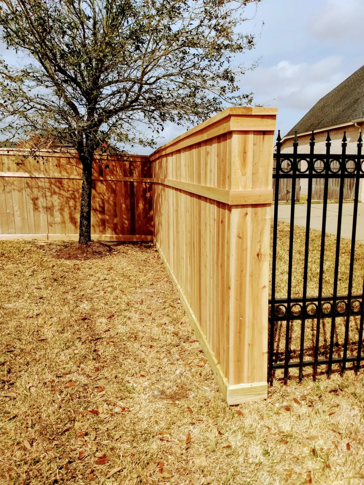 Cedar privacy fence tied into a black ornamental iron gate at a Cross Creek Ranch home in Fulshear