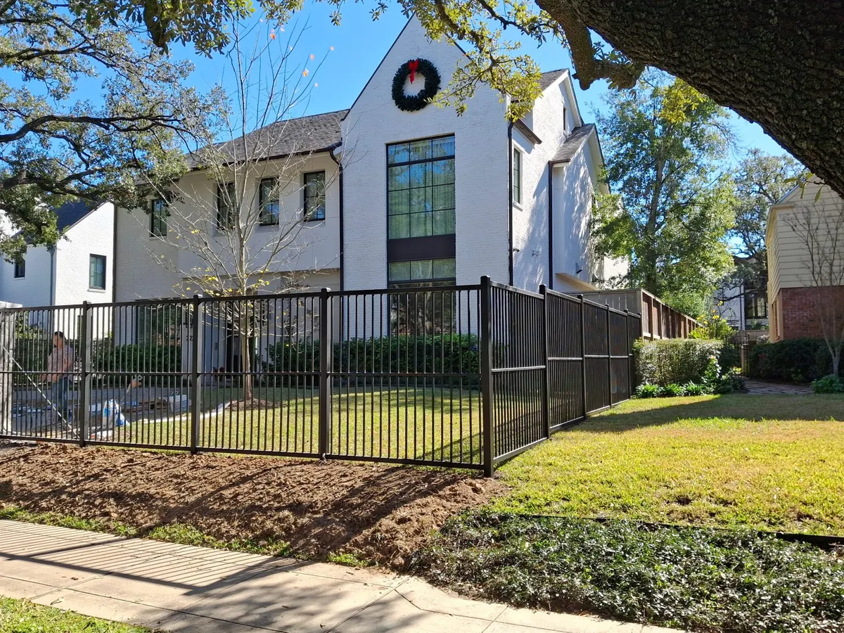 Black ornamental metal fence in front of a modern white home in Inwood