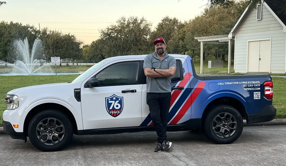 76 Fence team member standing beside a branded 76 Fence truck on a residential street