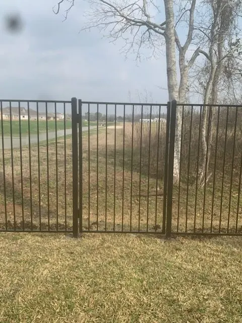 Black metal walk gate set into a fence line in Richmond