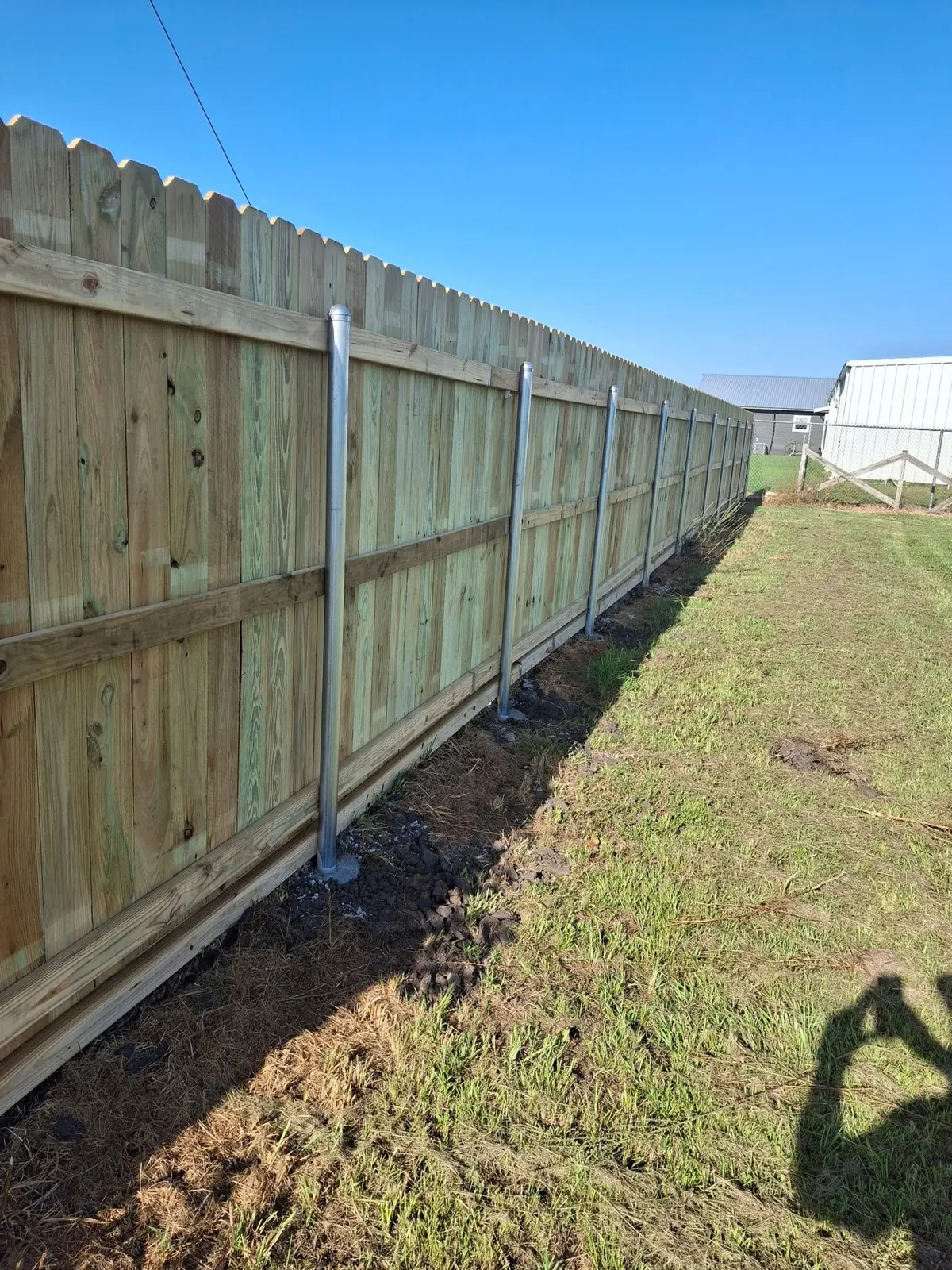 Long pressure-treated pine privacy fence with steel posts in Fulshear