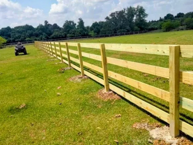 Three-rail wood pasture-style fence across an open field in Fulshear