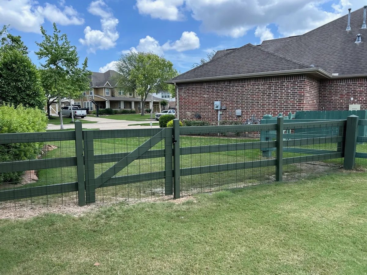 Green wood rail fence with wire mesh and gate across a Fulshear front yard
