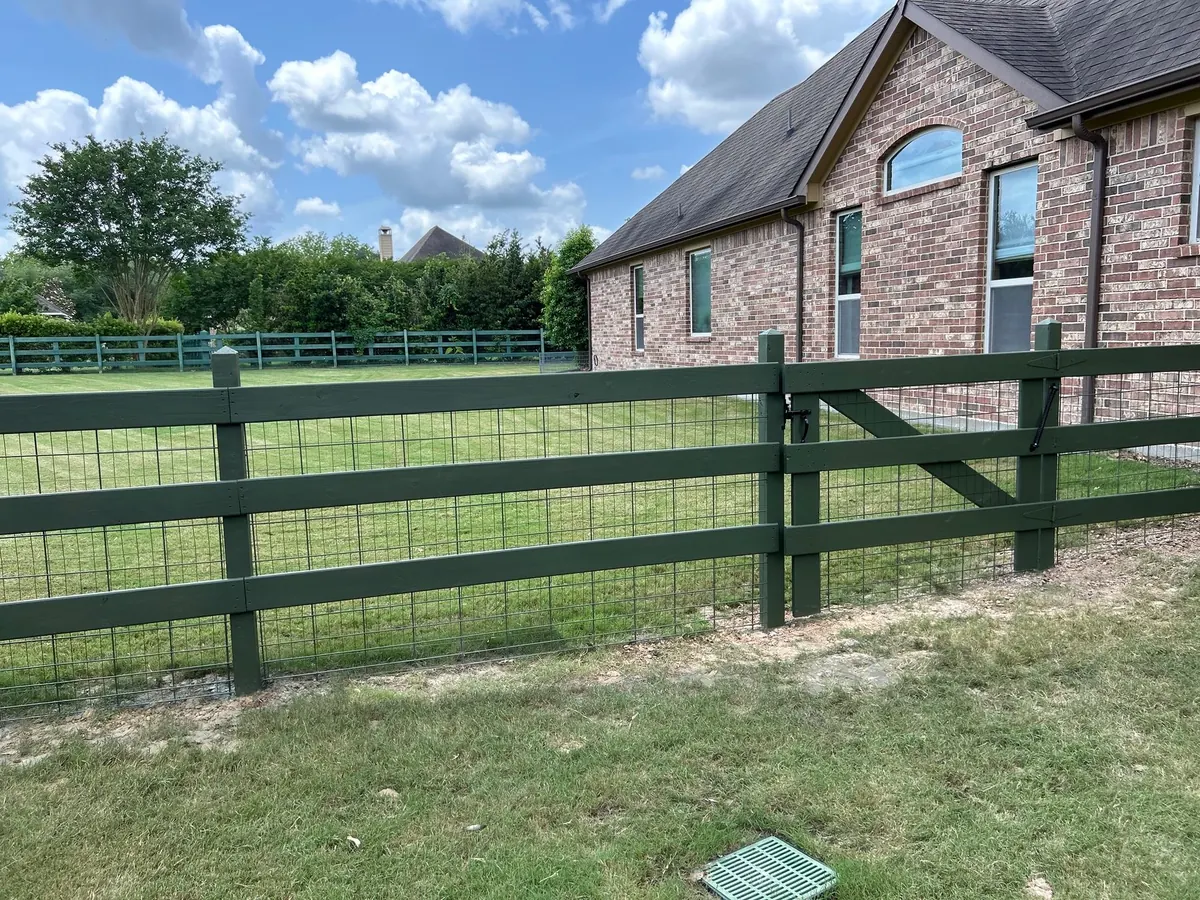 Green wood rail fence with wire mesh panels along a Fulshear home