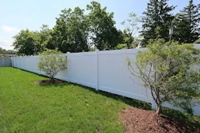 White vinyl privacy fence along a green lawn in Brenham